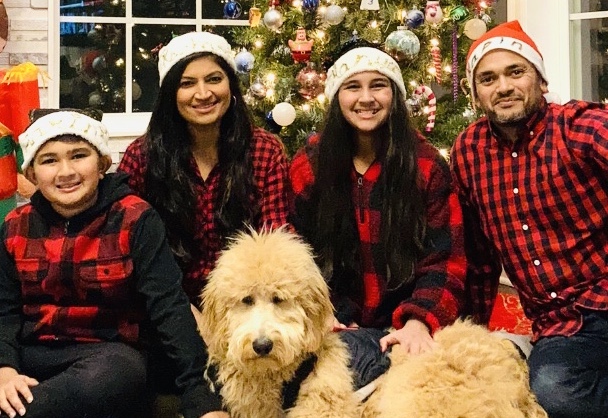 A photograph of Kapin Vora and his family and dog in coordinating red and black flannel Christmas outfits